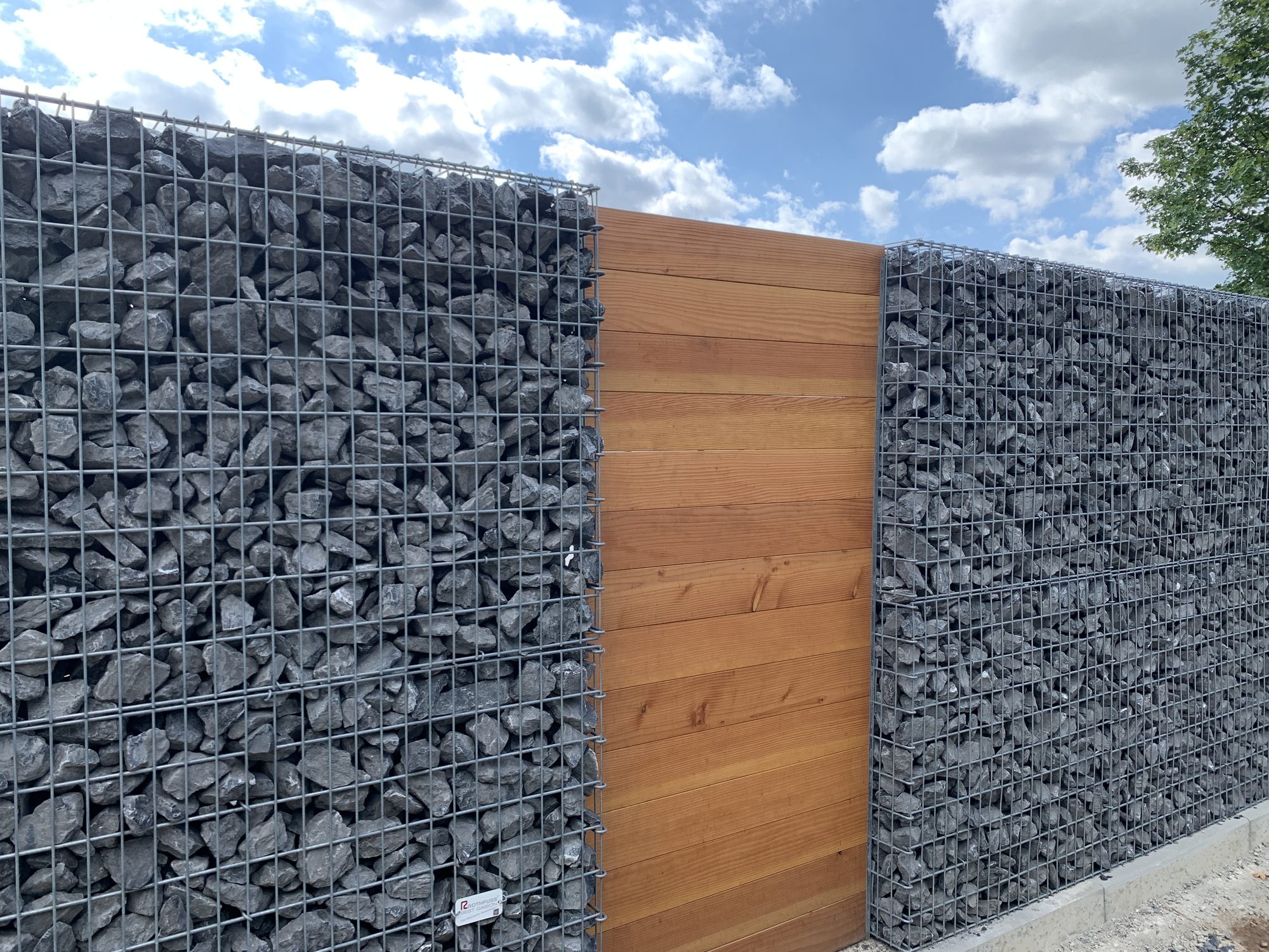 Blicks Professional Gabionenzaun kombiniert mit Holzelement und Basaltfüllung